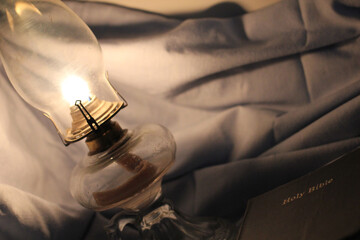 Lamp Beside a Closed Bible on a Sheet