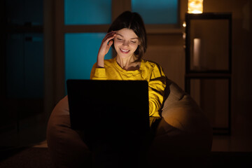 .The girl is happy. She works on a laptop at home. A creative woman has achieved success working on...