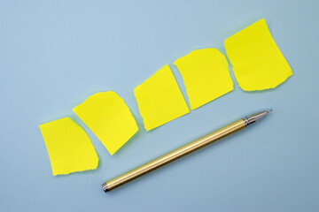 On a blue background, five sheets of yellow torn paper with a yellow pen. Space for text