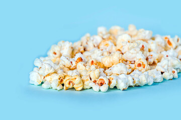 Fresh popcorn scattered on blue background. Cinema snack concept. Food for watching movie and...