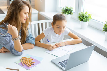 Mom helps her daughter with online homework.