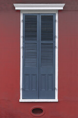 Fototapeta premium Blue wooden window with red shutters on the wall.