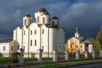 Fototapeta na wymiar Nikolsky (Nikolo-Dvorishchensky) Cathedral and Church of Paraskeva Friday against the backdrop of a gloomy sky on an October day. Veliky Novgorod, Russia
