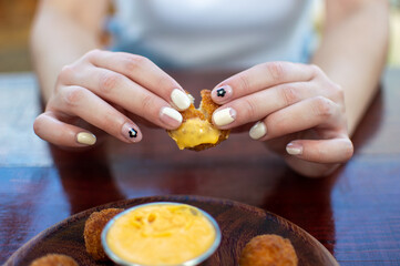 beautiful woman holding crispy fast food dipping in cheese sauce