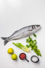European bass with spices and herbs ingredients  on chopping board over white textured background top view space for text.
