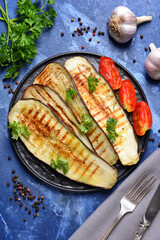 Tasty grilled eggplant in plate on color background