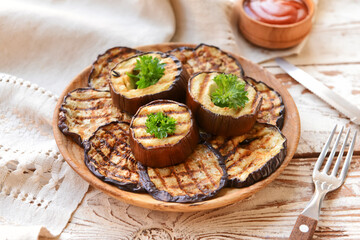 Tasty grilled eggplant in plate on wooden table
