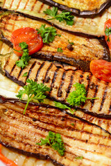 Tasty grilled eggplant with tomato and parsley, closeup
