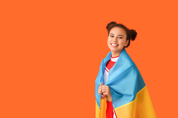 Beautiful young cheerleader with the flag of Ukraine on color background