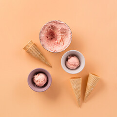 Homemade yogurt strawberry ice cream, sweet waffle cones on pastel pink background.