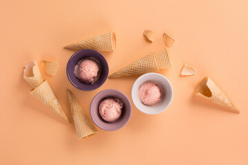 Homemade yogurt strawberry ice cream, sweet waffle cones on pastel pink background.