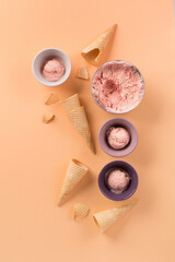 Homemade yogurt strawberry ice cream, sweet waffle cones on pastel pink background.