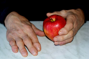 the old man's hands hold an apple