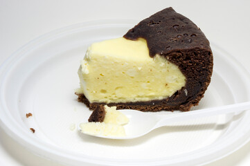 A piece of chocolate milk cake on a plate and a spoon