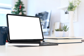 Comfortable workplace with tablet computer, notebook, coffee cup, and plant. Blank screen for graphic display montage.