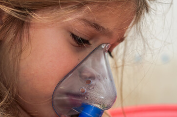 Little girl child makes inhalation with mask on face	
