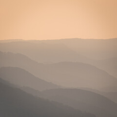 Foggy morning in the mountains. Layers of slopes in the early morning sun