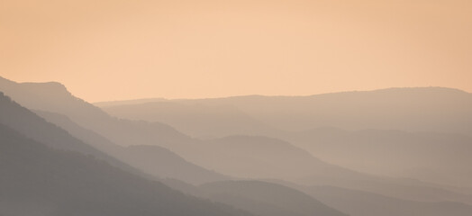 Foggy morning in the mountains. Layers of slopes in the early morning sun