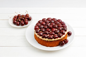 Homemade cake with cherries on white wooden table. Shallow focus.