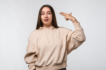 Young beautiful woman pointing hand and fingers to head like gun, suicide gesture