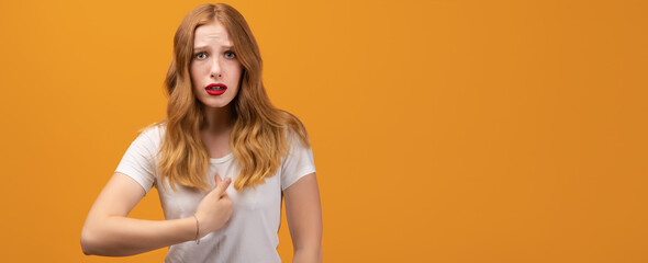 Indignant woman points at herself with for finger, has dissatisfied expression. Copy space