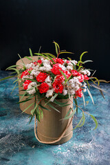 Composition of flowers and branches of eucalyptus in a round gift box. Vertical shot