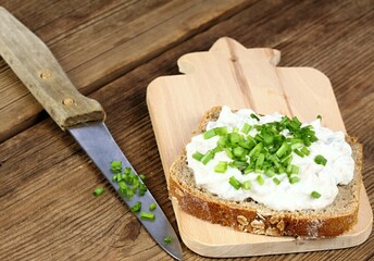 Cod liver pate  over brown bread with spring  green onion. Homemade spread made from cod liver, cottage cheese and cut pickles on wooden cutting board.