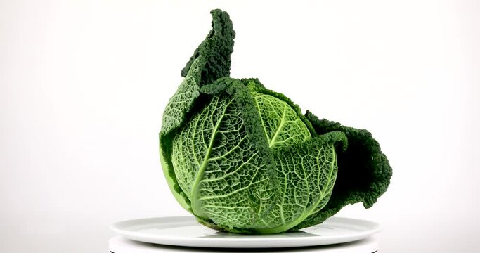 Green savoy cabbage rotating on white background, isolated vegetables, 4k close up. 