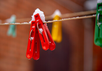 Bright colored clothespins covered with snow on a clothesline.