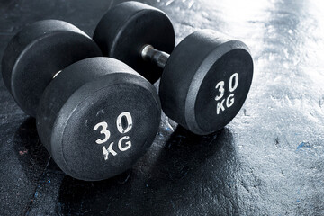A pair of heavy 30 kilogram dumbbells on rubber floor matting at the gym. Made with cast iron and...