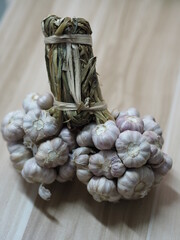 Garlic tied together in a bunch, placed on wooden table