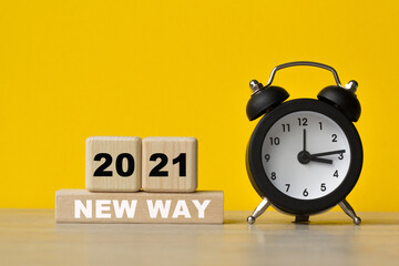 NEW WAY 2021 , text written on cubes, alarm clock on a yellow background. The concept of world business, marketing, finance.