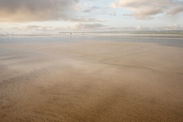 Warm wet yellow sand surface on a beach, Beautiful cloudy sky in the background. Nature scene