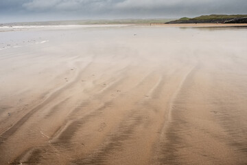 Warm wet yellow sand surface on a beach, Cloudy sky in the background. Nature scene