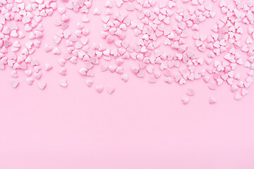Pink background. Pink hearts on a pink background. Hearts sprinkles. Valentine day. Flat lay style. Top view. Place for design. Sweet background. Confetti.