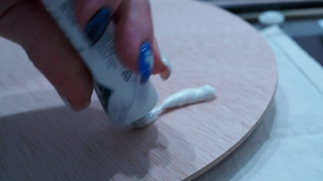 the girl squeezes oil paints on the palette.