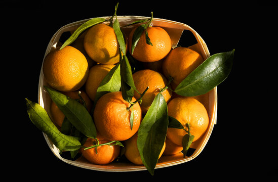Photo with natural light of some tangerines in a basket on a black background