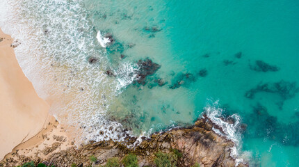 Aerial view over rocks landscape and waves splash on the beach at Naithon Beach, Phuket, Thailand