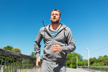 Fototapeta premium fitness, sport and healthy lifestyle concept - happy young man running across city bridge
