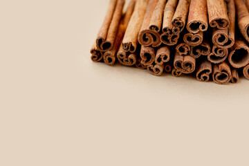 many sticks of high-quality cinnamon lie in a pile on a beige background. savoury spices for cooking. Monochrome food photography, selective focus, space for text