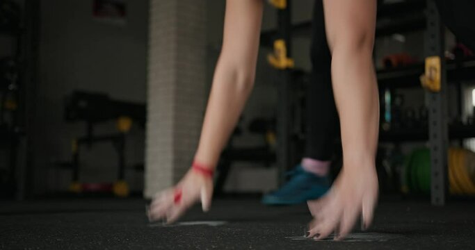 Muscular sportswoman doing burpee exercise. Tracking shot of blond female athlete doing squat thrust exercise during intense workout in gym