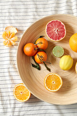 food, healthy eating and vegetarian concept - close up of citrus fruits on wooden plate