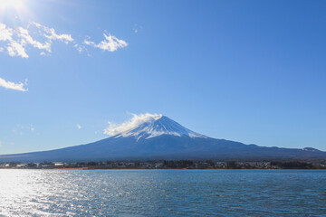 Mount Fuji is in front of a lake. There is a blue sky as the copy space background.