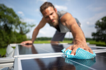 Man wiping a solar panel on the roof of a camper van