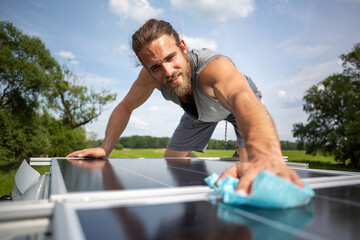 Man wiping a solar panel on the roof of a caravan - obrazy, fototapety, plakaty