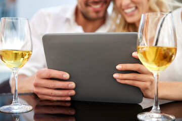 people, technology and dating concept - close up of happy couple with tablet pc computer and wine at restaurant