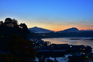 An early morning view with beautiful colorful lights Before sunrise At the Fisherman Village near Mon Market at Mon Bridge, Sangkhlaburi District, Kanchanaburi Province, Thailand