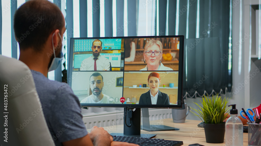 Poster back view of man with mask talking on video call with remotely colleagues. freelancer working in new