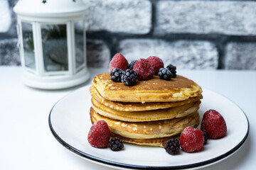 A stack of blackberry and strawberry pancakes on a plate.