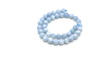 Obraz premium Aquamarine bead strand on white background. Copy space is on the left side. 